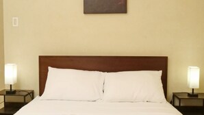 Una habitación de hotel con una cama, dos lámparas de noche y un cuadro en la pared.