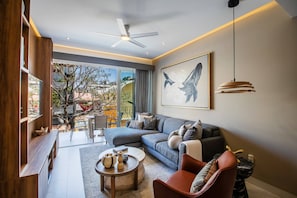 A modern living room with a sofa, armchair, coffee table, and artwork on the wall. - Romantic Zone 2BR | Rooftop Pool, Bar & Views (Puerto Vallarta)