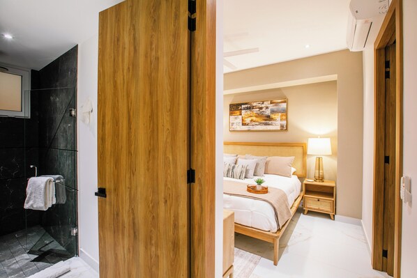 A modern bathroom with a glass shower enclosure and a wooden door.