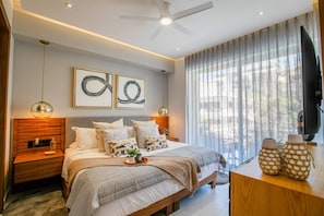 A modern bedroom with a bed, bedside tables, a desk, and a TV.