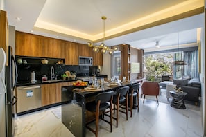 Une cuisine moderne dotée d’un îlot central, d’un coin repas avec des chaises et d’un salon avec un canapé et une table basse.