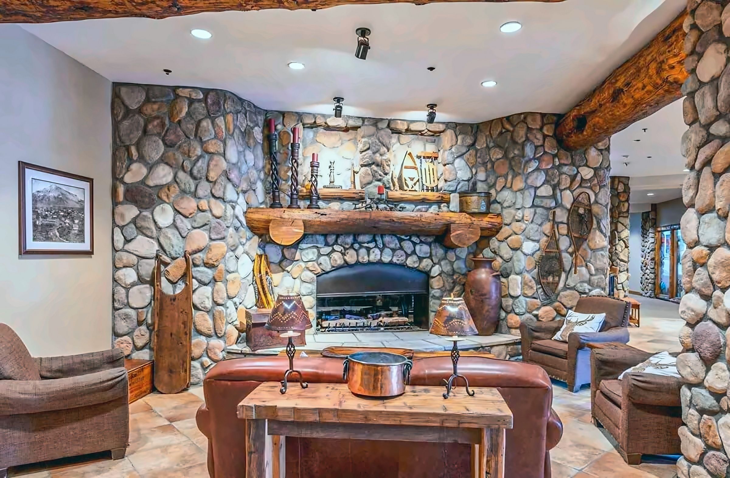 A stone-walled interior with a fireplace, leather seating, and rustic decor.