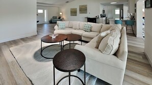 Ein großzügiger Wohnbereich mit Ecksofa, zwei runden Couchtischen und Deckenventilator.