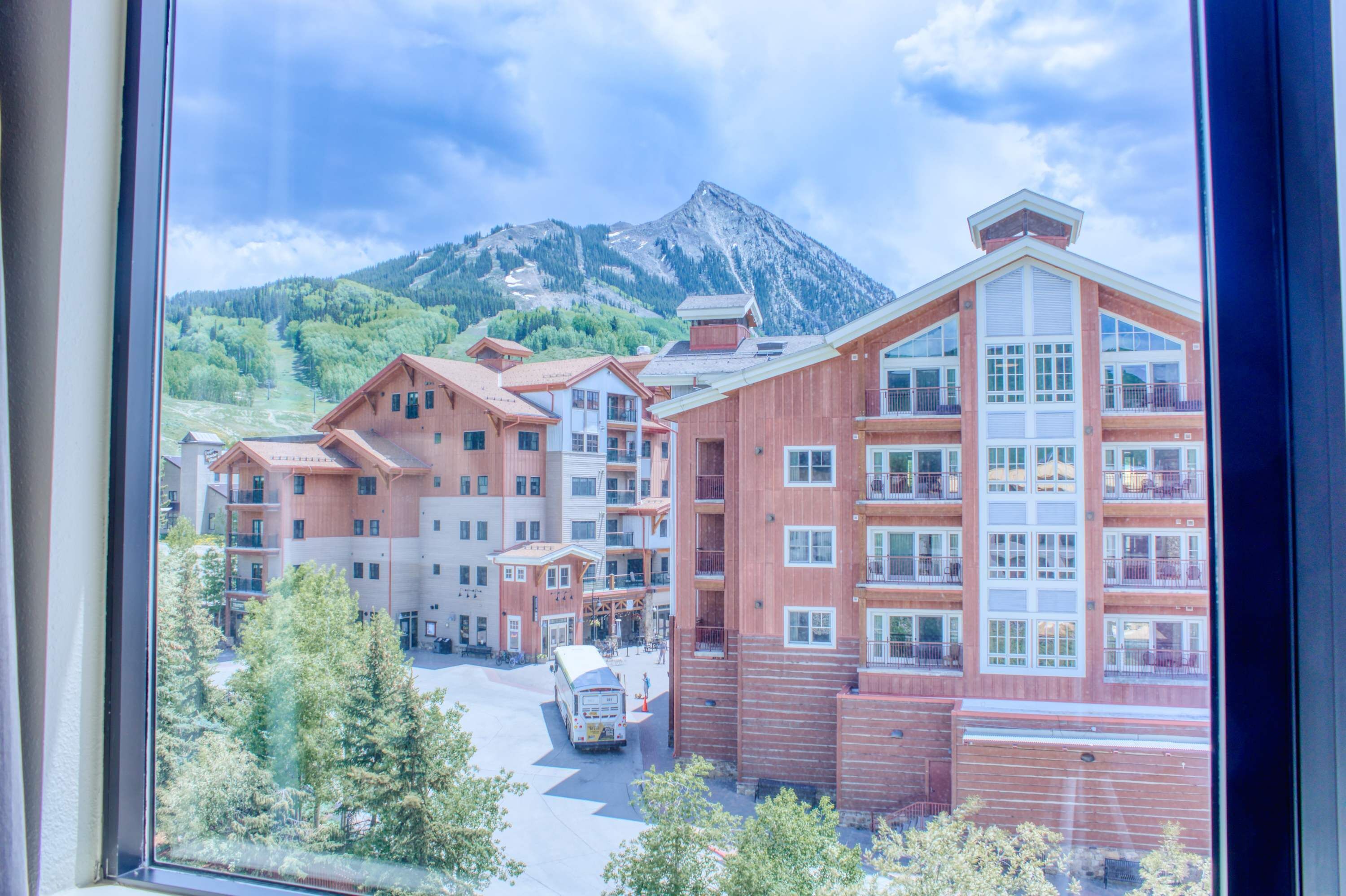 A multi-story hotel with a mountain backdrop, featuring balconies and a central courtyard.