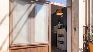 Una puerta de madera con un panel de vidrio esmerilado, una lámpara colgante y un pequeño estante con adornos.