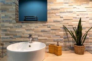 Ein Badezimmer mit einem großen, weißen Waschbecken, einer Holzwand mit blauem Akzent und einer Topfpflanze.