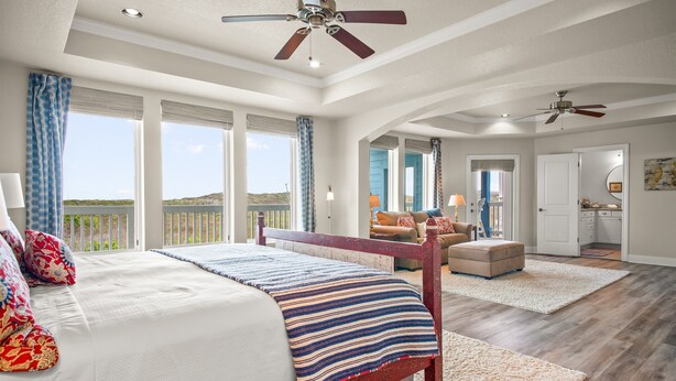 A spacious bedroom with a large bed, a ceiling fan, and a view of the outdoors.