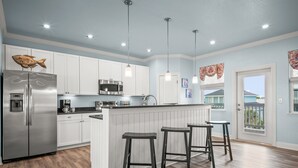 A modern kitchen with white cabinets, stainless steel appliances, and a wooden island with bar stools.