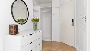 Ein modernes Badezimmer mit einem weißen Waschtisch, einem runden Spiegel und einer Blumenvase.