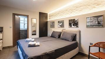 Un dormitorio con cama, una silla, armario y cuadros en la pared.