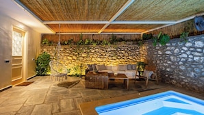 Een wellnessruimte met een stenen muur, een houten plafond en een whirlpool.