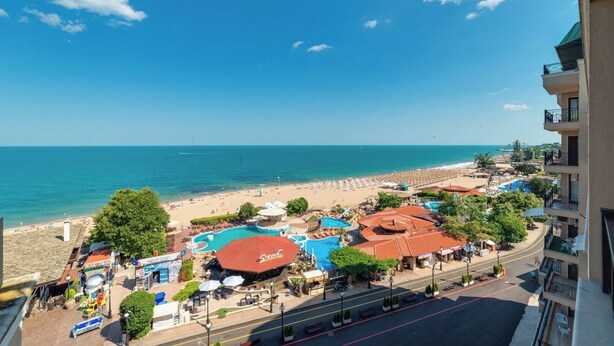A beachside resort with a pool, umbrellas, and a view of the ocean.