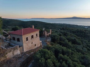 Un edificio in pietra con tetto rosso, immerso nel verde e affacciato sulla costa.