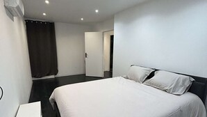 Un dormitorio moderno con una cama grande, una mesita de noche y un armario.