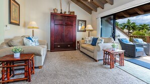 Una sala de estar con un mueble de madera grande, dos sofás, una mesa de centro y vistas al exterior.