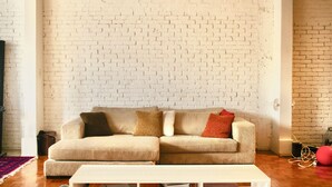 A living room with a white brick wall, a striped sofa, and a white coffee table.