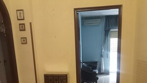 A room with a marble floor, a wooden door leading to another room, and two chairs.