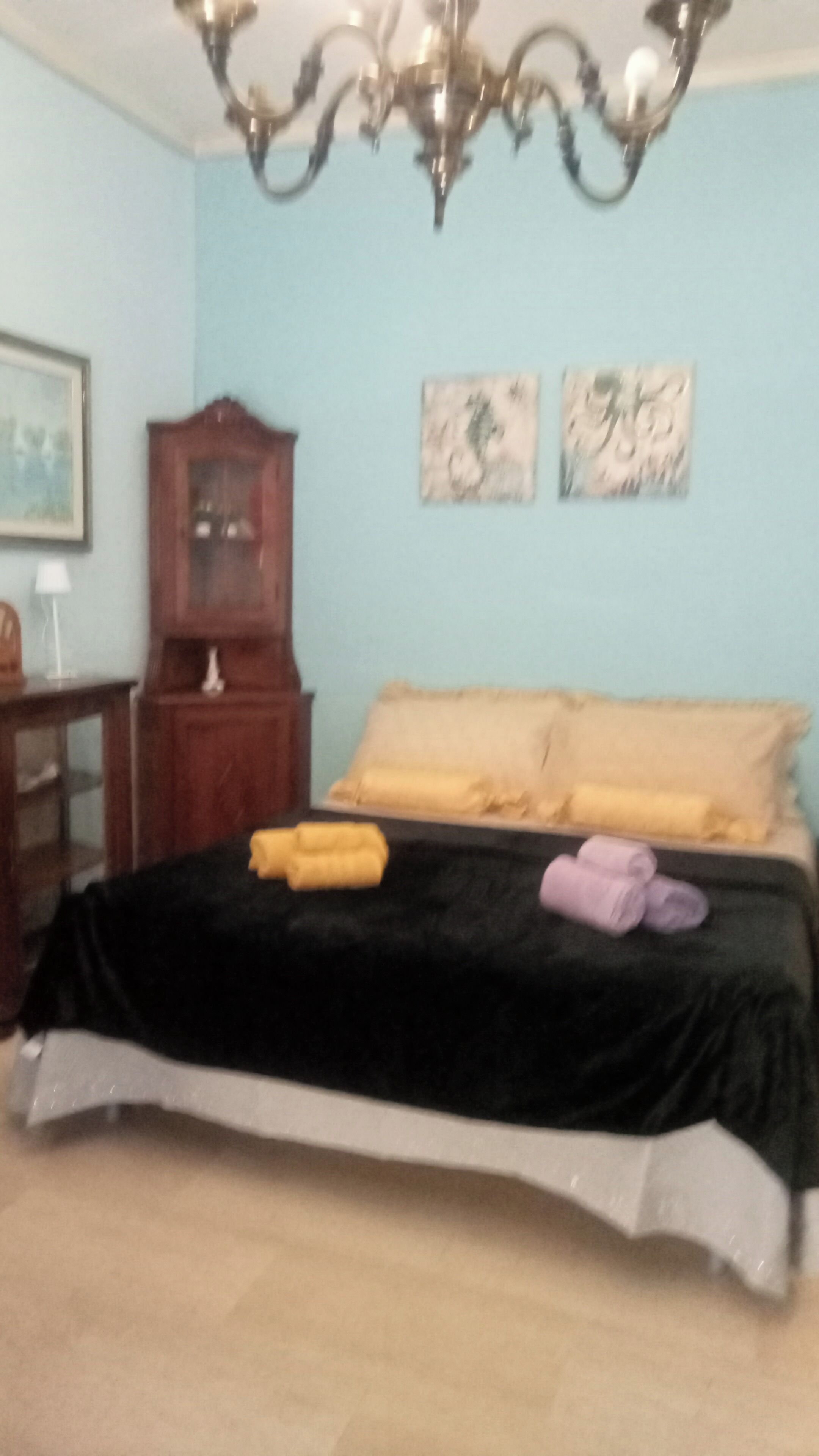 A bedroom with a bed, a wooden cabinet, and two wall art pieces.