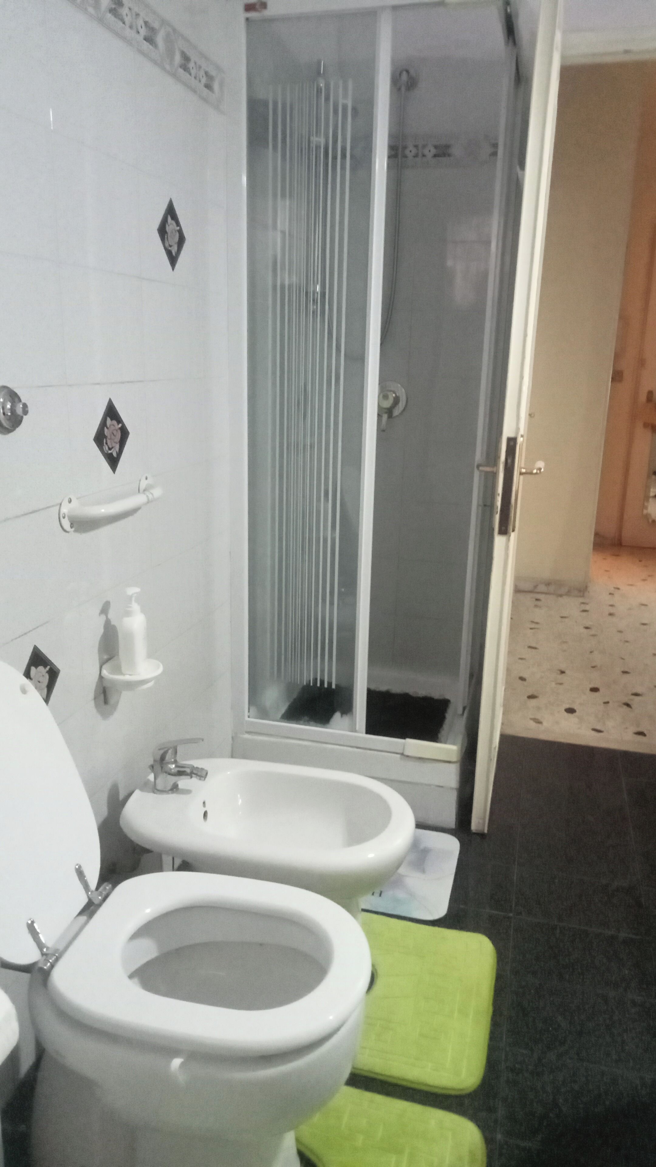 A bathroom with two toilets, a sink, and a glass-enclosed shower stall.