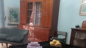 A room with a bed, a wooden cabinet, a chair, and a small table.
