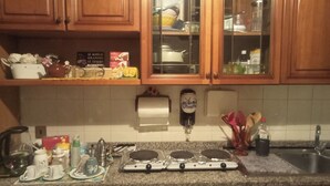 A kitchen with wooden cabinets, a granite countertop, a stove, and various kitchen utensils.