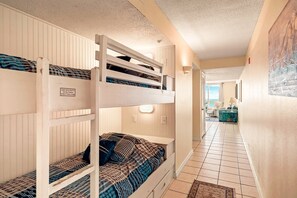 A corridor with bunk beds, a door leading to a balcony, and a tiled floor. - Pelican Beach 0602 1 Bedroom Condo (Destin)