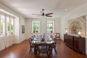 A dining room with a large wooden table, chairs, a ceiling fan, and a decorative wall piece. - Rosedale 3 Home (Worthing)