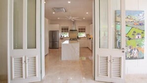 A modern kitchen with a central island, a refrigerator, and a ceiling fan. - Rosedale 3 Home (Worthing)