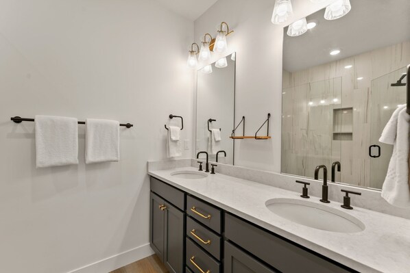 A modern bathroom with two sinks, a large mirror, and a towel rack. - Periwinkle Sky 3 Bedroom Condo (St. George)