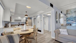 Una cocina moderna con armarios blancos, una mesa de comedor de madera y un sofá color beige.