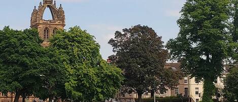 Een groot, open grasveld met een historische stenen toren op de achtergrond.