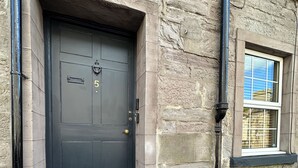 Un edificio de piedra con una puerta negra, el número 5, y una ventana pequeña con marco negro.