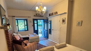 A room with a bed, a sofa, a chandelier, and a door leading to an outdoor area. - Dafne Konukevi (Bozcaada)