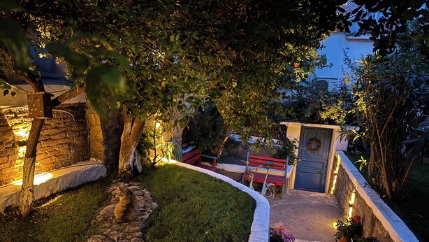A garden pathway with a stone border, a wooden bench, and a small gate. - Dafne Konukevi (Bozcaada)