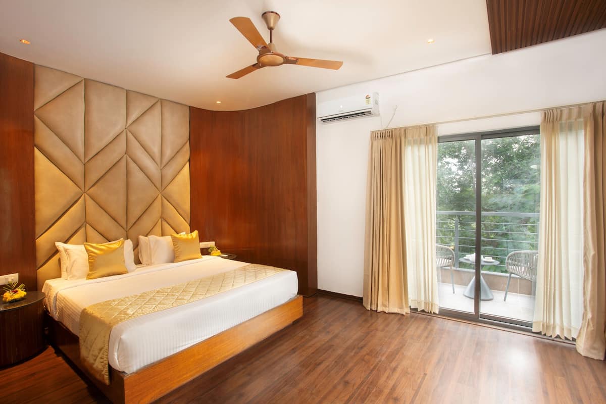A modern bedroom with a large bed, a ceiling fan, and a balcony with outdoor seating.