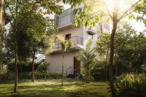 Ein modernes Gebäude mit Balkon, umgeben von Grünflächen und einem gepflegten Rasen.