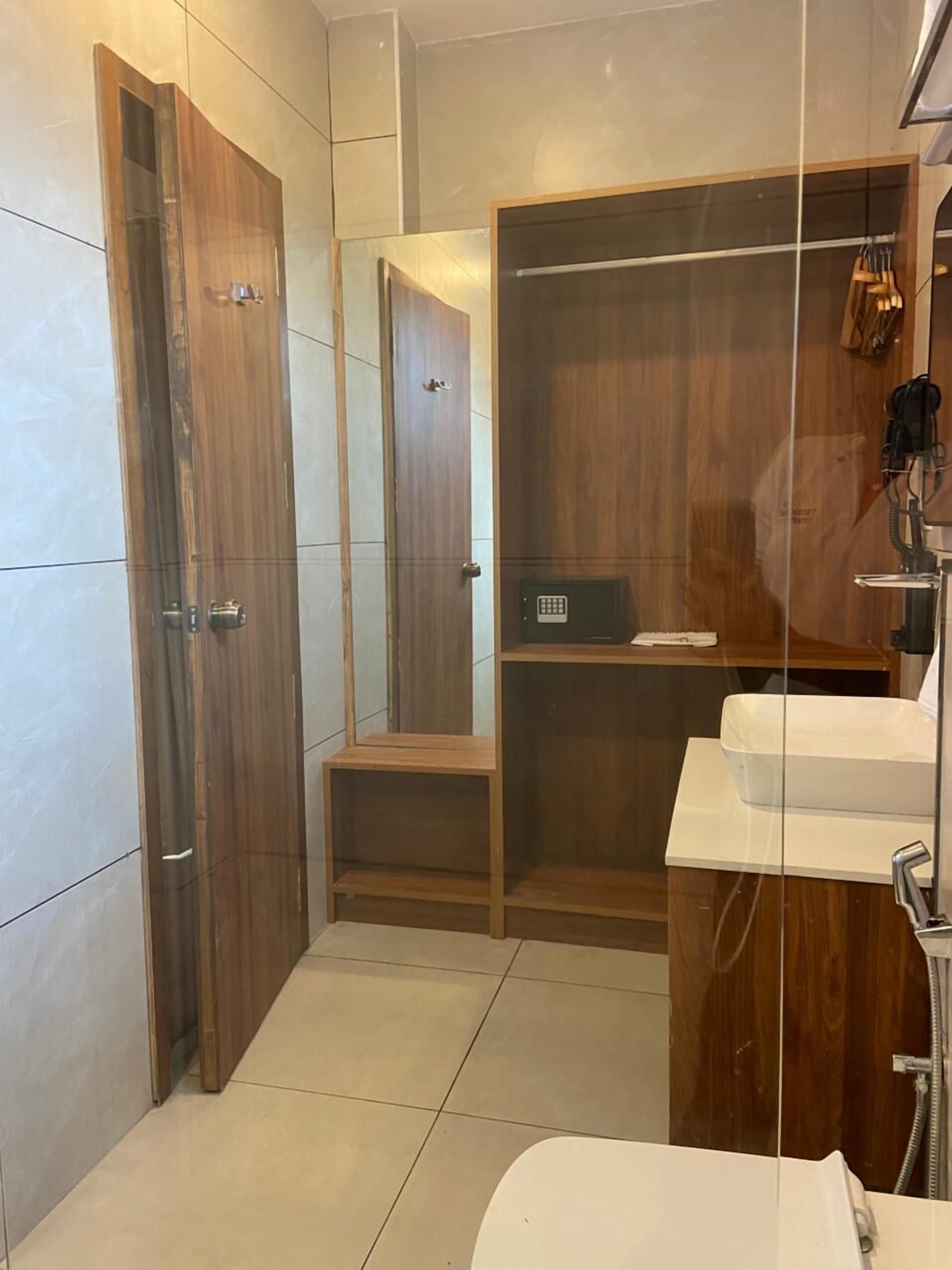 A modern bathroom with a wooden vanity, a glass shower enclosure, and a built-in storage cabinet.