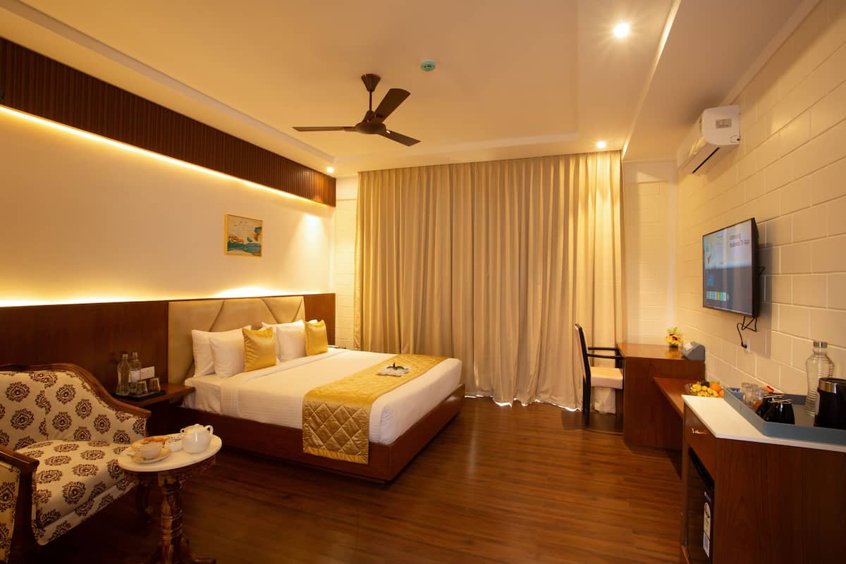 A hotel room with a bed, bedside table, chair, desk, and a TV.
