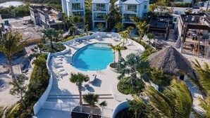 Een resort met een groot zwembad, meerdere gebouwen en uitzicht op de oceaan.