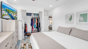 A bedroom with a large bed, a wardrobe, a television, and a ceiling fan.