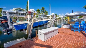 A marina with boats docked, a covered seating area, and a building with a balcony.