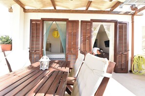 Ett träbord med en vit kudde och en lykta, placerat under en träpergola.