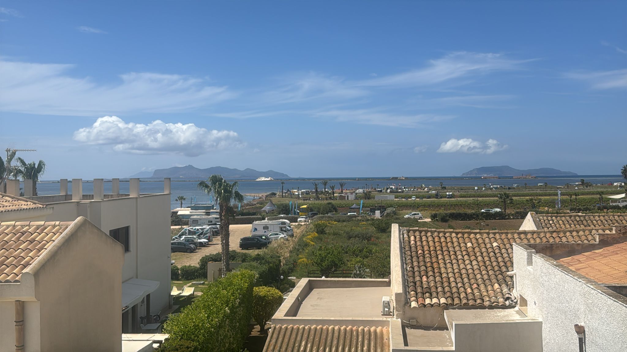A coastal view with buildings, parked cars, and a clear sky.