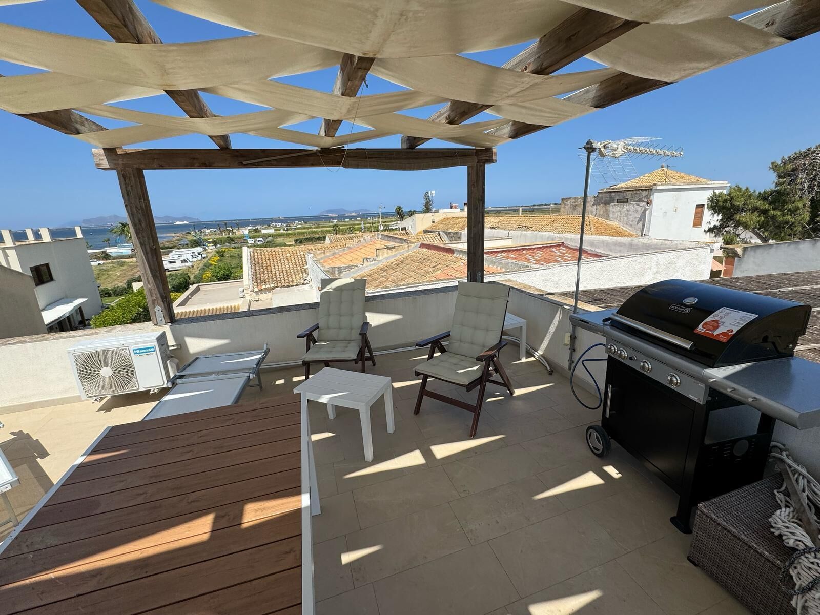Une terrasse sur le toit, agrémentée d’une pergola, de deux chaises, d’un barbecue et d’une table.