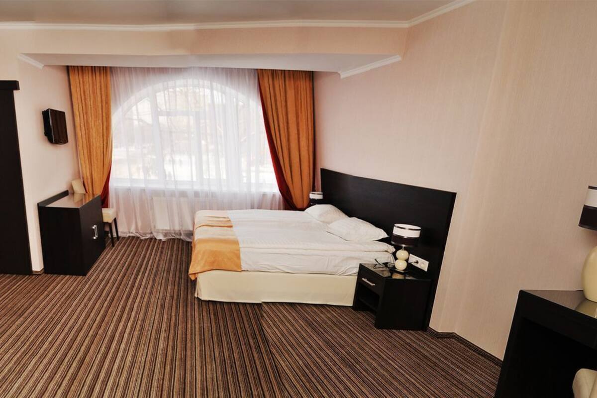 Habitación de hotel con una cama grande, un escritorio, una silla, una mesita de noche y una lámpara.