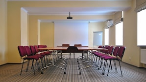 Une salle de conférence équipée d’une longue table et de nombreuses chaises, d’un projecteur et d’un tableau blanc.