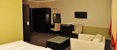 A hotel room with a bed, a desk, a chair, a television, and a small table.