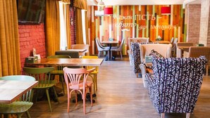 L’intérieur de ce restaurant, chaleureux et accueillant, est agrémenté de tables et de chaises en bois, d’un mur en briques rouges et d’un mur décoré de panneaux en bois aux couleurs vives.
