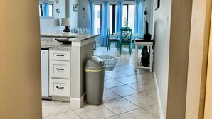 A kitchen with a central island, a dining area with green chairs, and a ceiling fan.
