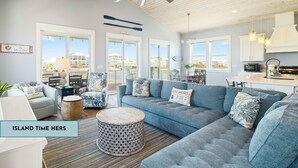 A spacious living room with a large gray sectional sofa, a round coffee table, and a ceiling fan. - Island Time Hers by Liquid Life (Gulf Shores)